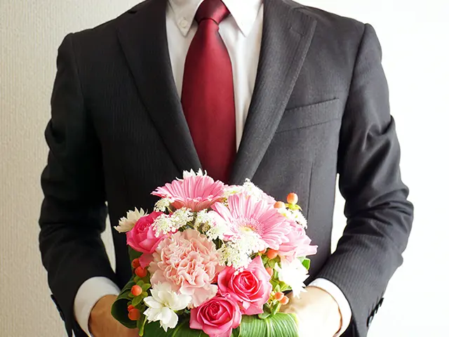 ガーベラの花束を持つ男性