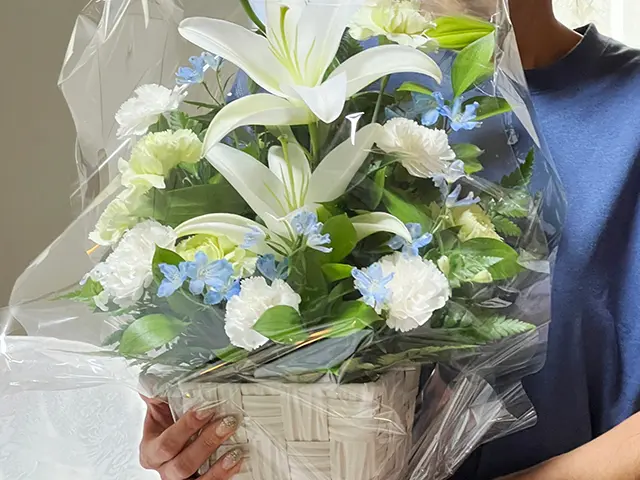 白いユリの供花を持つ女性