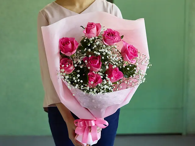 ピンクバラの花束を持つ女性