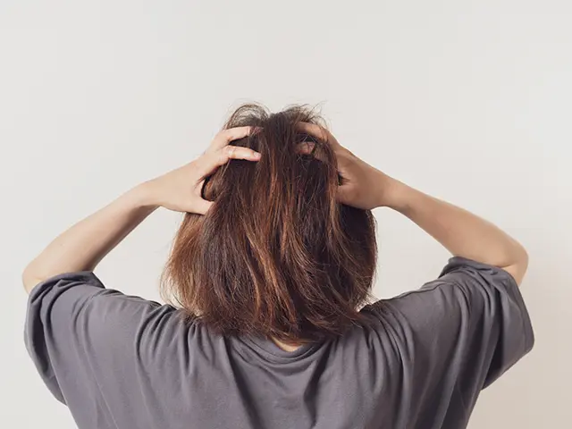 頭を抱える女性の後ろ姿