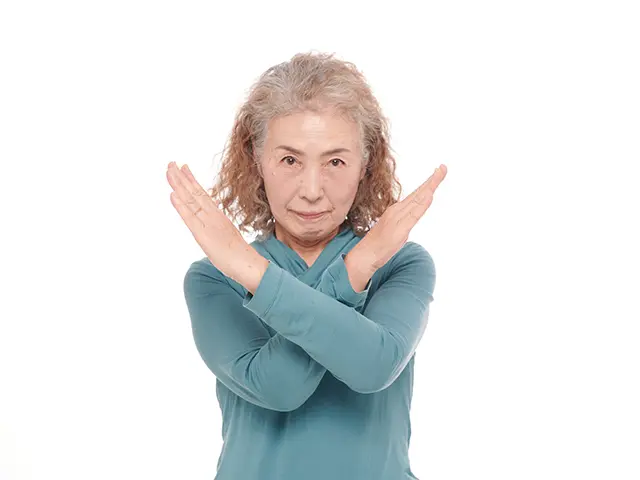 バツマークを出すシニア女性