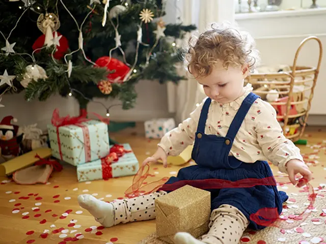 クリスマスツリーの前でプレゼントを開ける子供